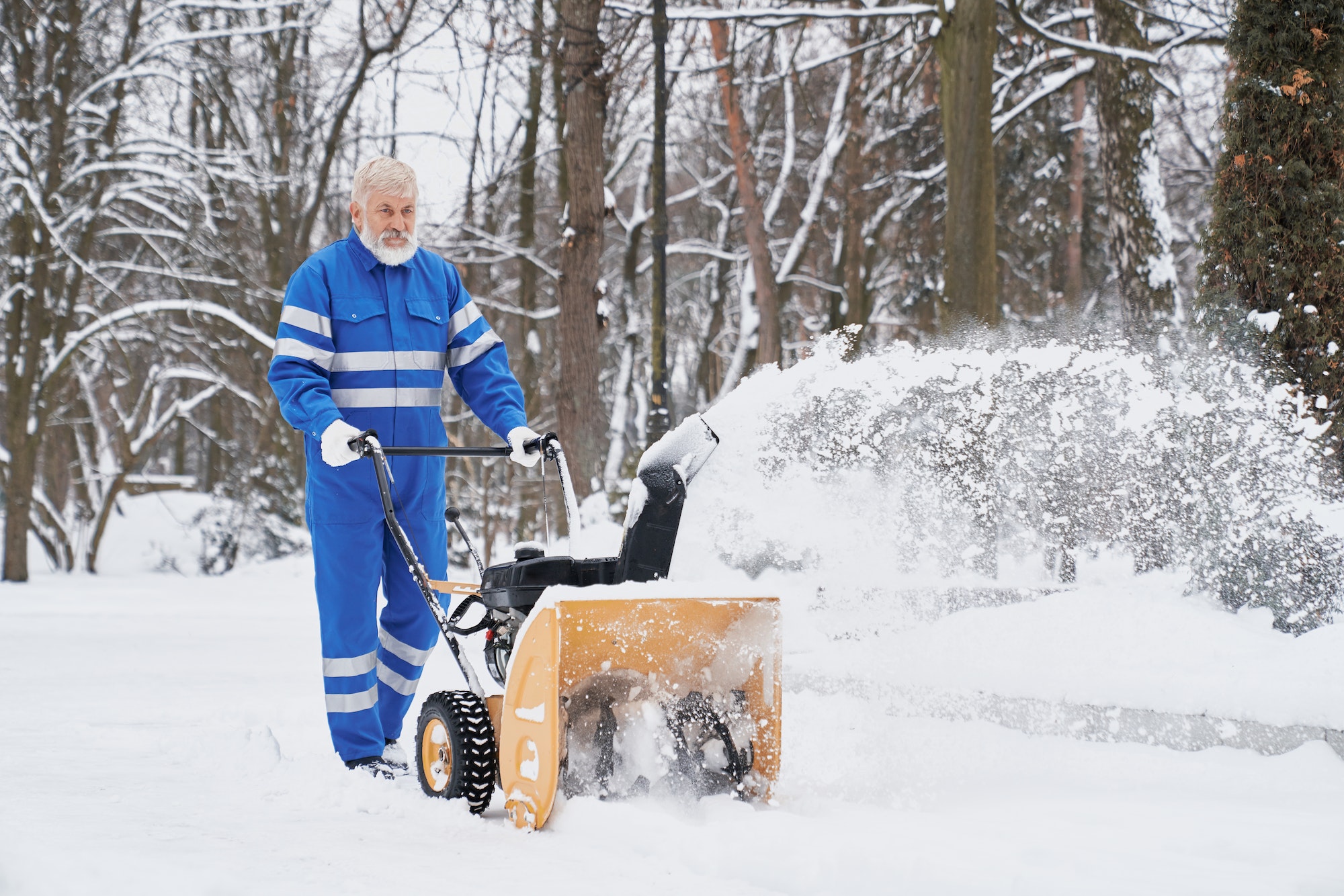 Man working with snowblower and removing snow from footpath